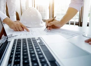 Architekten und Bauleiter bei der Bauplanung mit Laptop und Bauplänen – Kunstreich Bauunternehmung